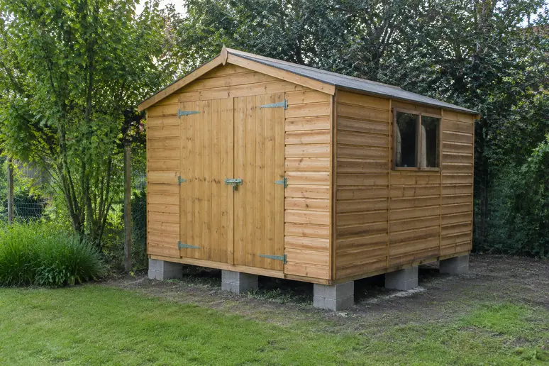 Abri de jardin en bois posé sur des plots en béton pour éviter l'humidité