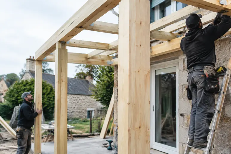 Ossature en bois claire d'une extension de maison en cours d'assemblage sur chantier