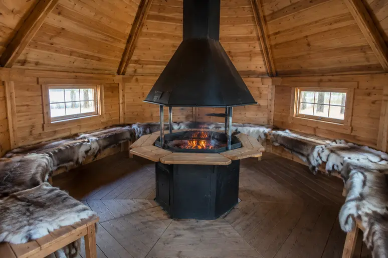 Intérieur d'un kota finlandais traditionnel aménagé autour de son foyer central en bois