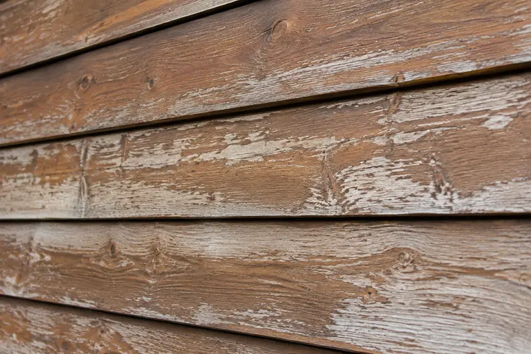 Détail d'une lasure bois extérieur qui commence à s'écailler sur un bardage en bois vieilli