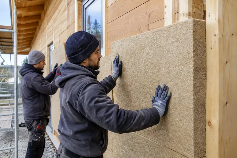 Pose de l'isolation thermique par l'extérieur sur les murs d'un lodge en bois habitable.