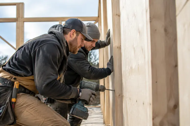 Ouvriers assemblant les panneaux d'une maison bois en kit sur un chantier de construction