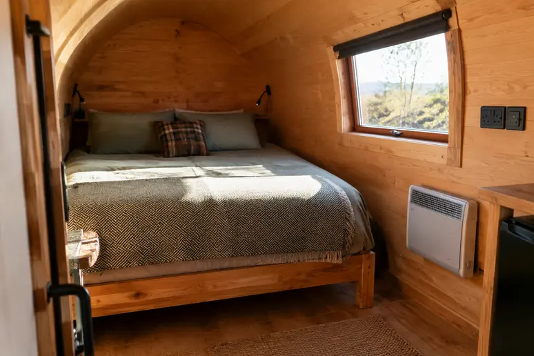 Intérieur aménagé d'un pod de camping équipé avec couchage et raccordement électrique