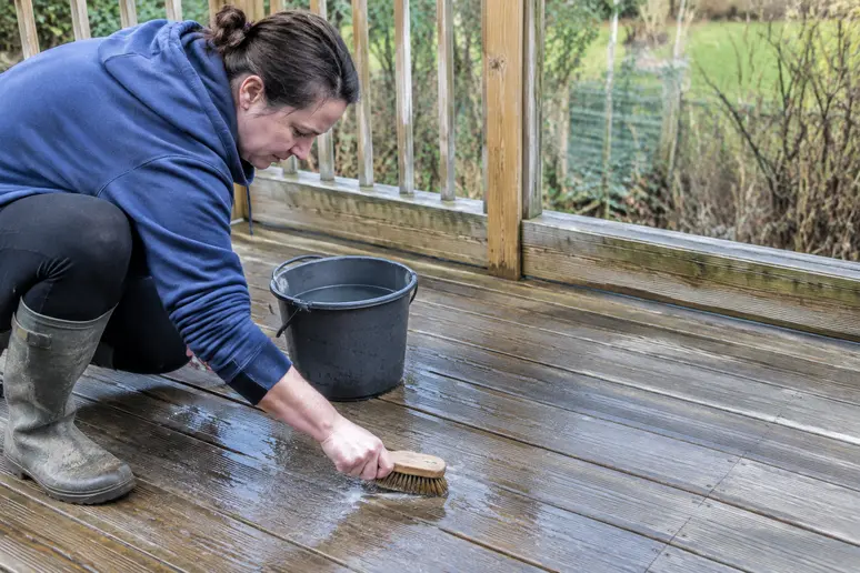 Nettoyage d'une terrasse en bois avant d'appliquer un saturateur bois.