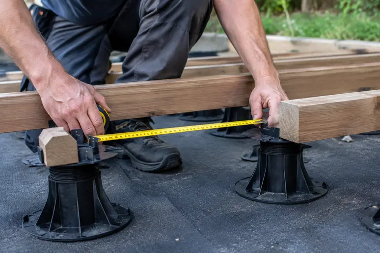 Mesure de l'entraxe entre les plots réglables et les lambourdes de la terrasse bois sur plot.